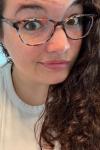 White woman with thick rimmed glasses and brown hair