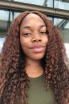 Black girl smiling with curly brown hair and olive color shirt